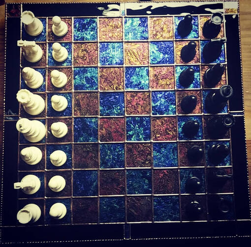 stained glass chessboard in copper and blue with black and white chess pieces